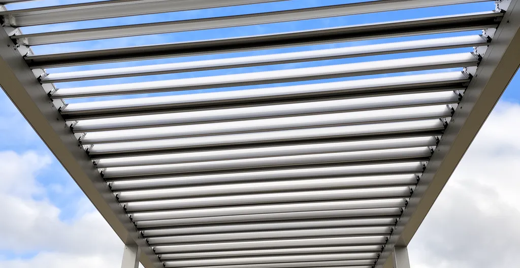 Lames orientables aluminium pergola bioclimatique en position semi-ouverte avec ciel visible