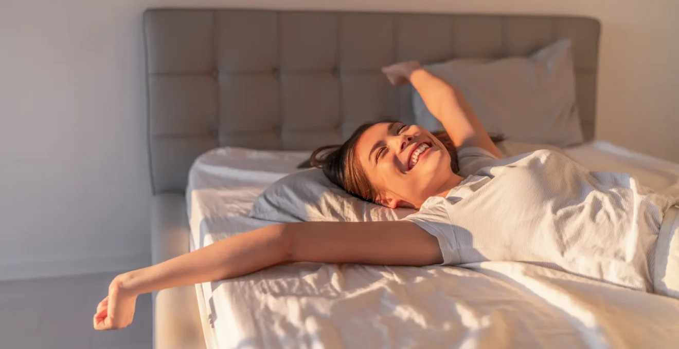 Une conseillère soulève la surface quiltée d'un matelas haut de gamme pour montrer les ressorts ensachés et les couches de matériaux naturels, dans une chambre élégante à la française.
